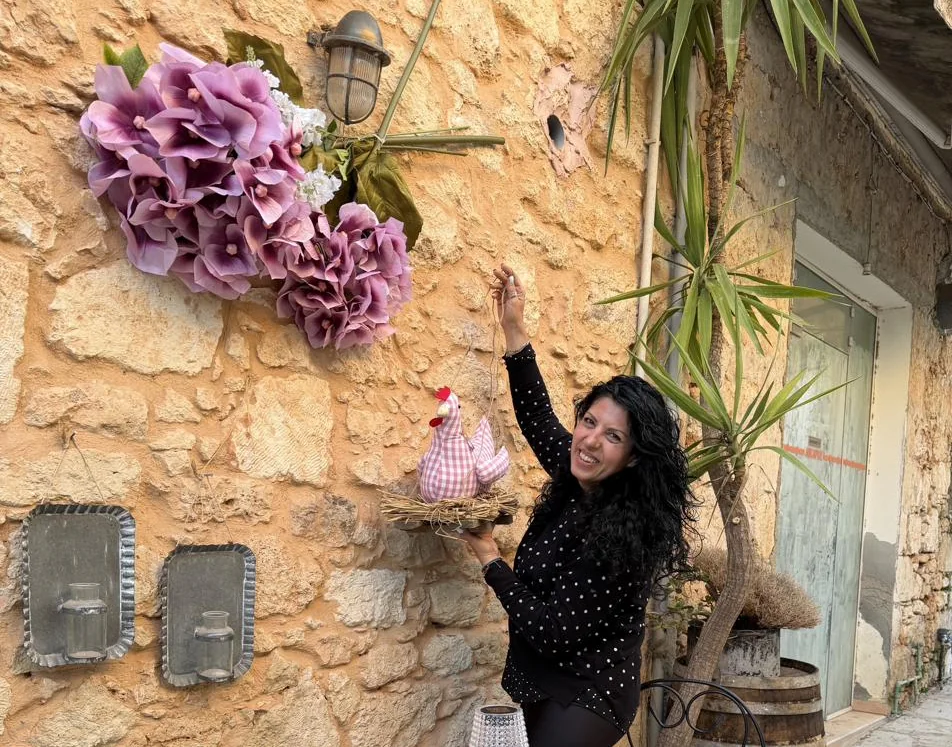 Katerina at the Carob \& Olive stone wall exterior with flowers and décor